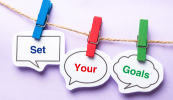 Set your goals paper bubbles with clip hanging on the line against purple background.