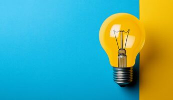 Light bulb on a blue and yellow background, representing the idea of innovation, inspiration, creativity, and the concept of thinking outside the box.