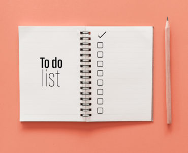 Notebook and pencil with to do list words on pastel color background.