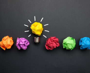 Great idea concept with crumpled colorful paper and light bulb on black background