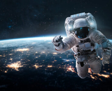 Astronaut in the outer space over the nightly planet Earth. City lights. Abstract wallpaper. Spaceman. Elements of this image furnished by NASA