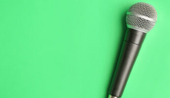 Modern microphone on color background