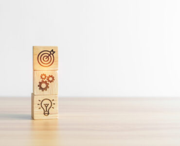 dartboard above Gear and Lightbulb icon block on desk. business planning process, goal, strategy, target, mission, action, objective, teamwork and idea concept