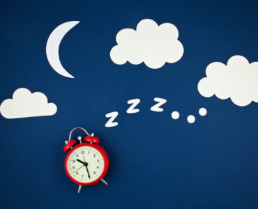 Snoring classic alarm clock on blue pastel trendy background. Flat lay, top view mock up. Minimal concept of rest, quality of sleep, good night, insomnia, relaxation