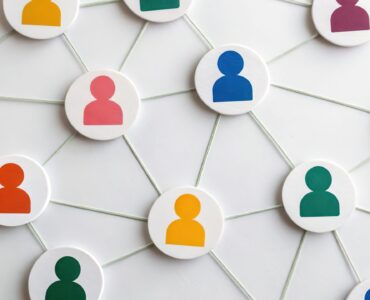 Colorful icons of people connected by lines, representing a network or social connections on a white background.