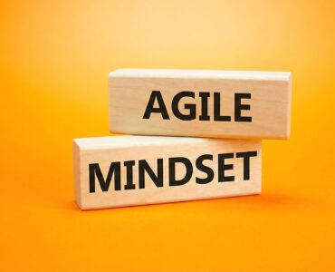 Agile Mindset symbol. Wooden blocks with words Agile Mindset. Beautiful orange background. Business and Agile Mindset concept