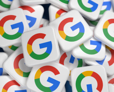 Logos of the company Google / Alphabet on a heap on a table. Full frame, elective focus.